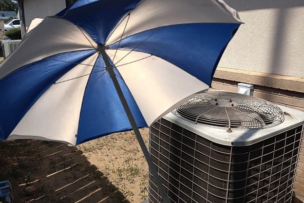Large umbrella shielding outside air condenser from sunshine.