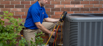 someone in a blue polo using a maintenance tool on an air conditioner