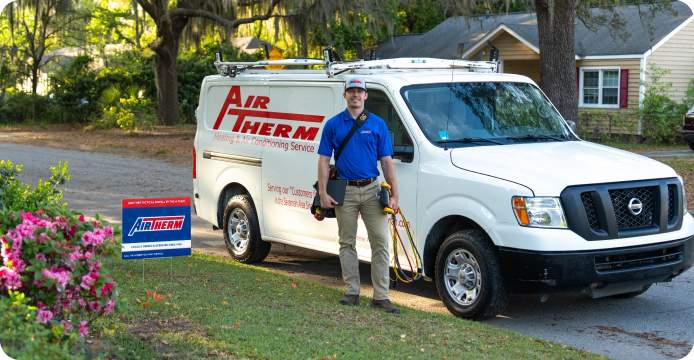 A technician in a blue polo standing in front of a work van