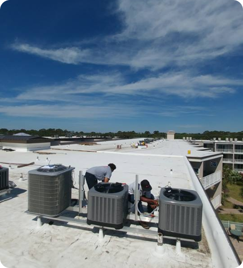 people on a roof servicing air conditoning units for a commercial building